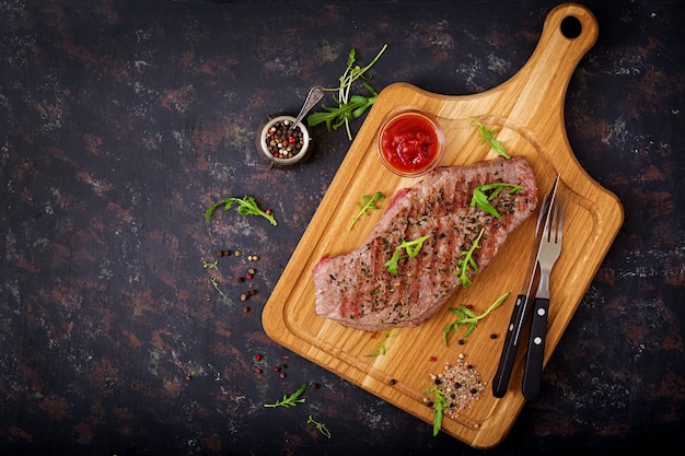 Manzo raro bistecca succosa con spezie su una tavola di legno. vista dall'alto. distesi.