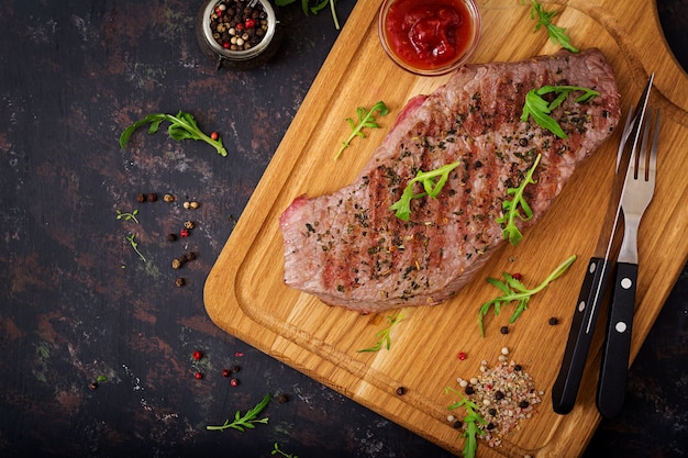 Juicy steak rare beef with spices on a wooden board. Top view. Flat lay.