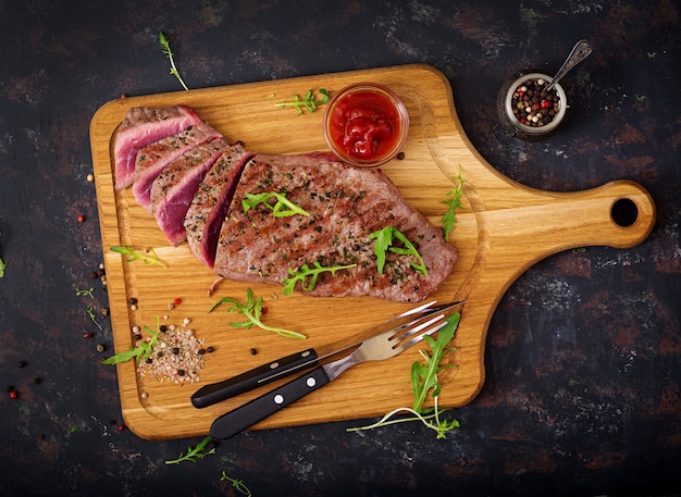 Juicy steak rare beef with spices on a wooden board. .