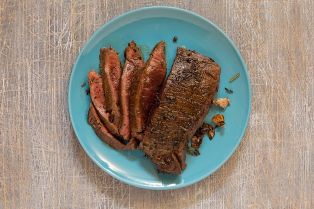 Juicy steak with blood fried in a pan top view traditional food