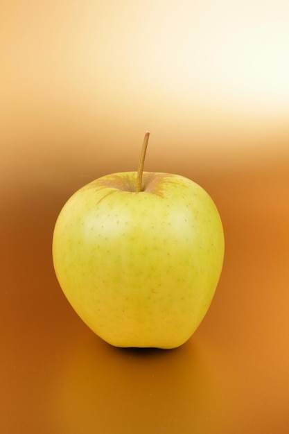 Juicy sweet green apple on a golden background Healthy food concept Closeup of a green fruit