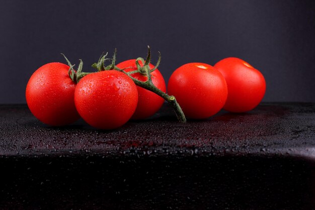 Juicy sweet red tomatoes on a black background Healthy food concept Closeup