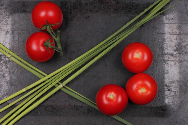 Juicy sweet red tomatoes and green sprigs on a black background Healthy food concept Closeup