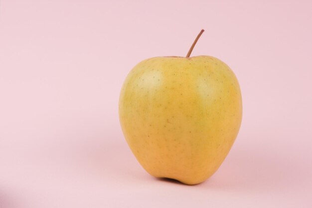 Juicy sweet whole apple on a pink background Healthy food concept Closeup of a sweet fruit