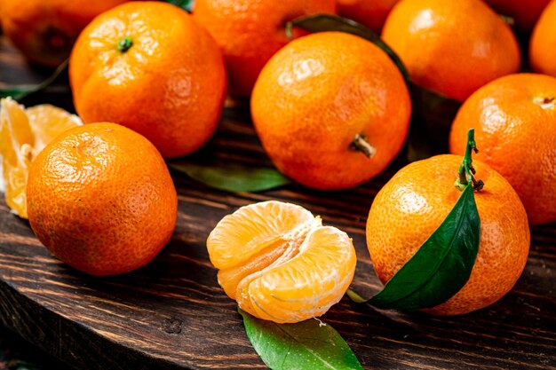 Photo juicy tangerines with leaves on a wooden tray