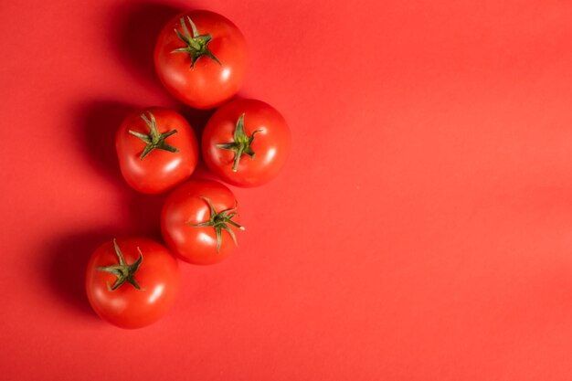 Juicy tomatoes on a bright red surface