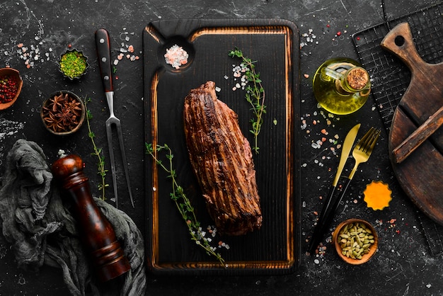 Juicy veal steak with spices on a black wooden board Top view Grilled meat