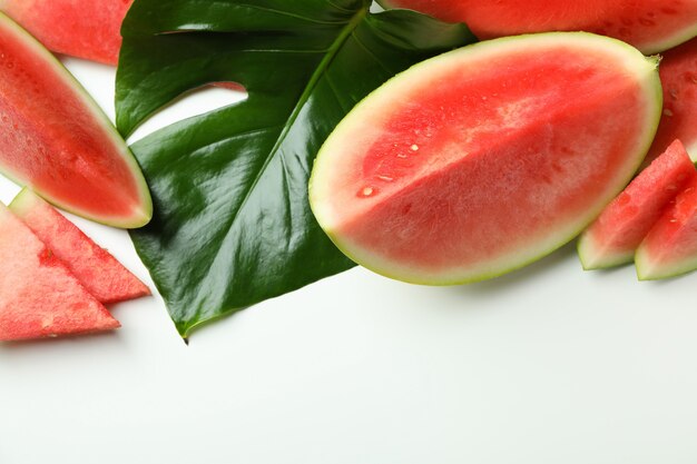 Juicy watermelon slices and palm leaf on white background