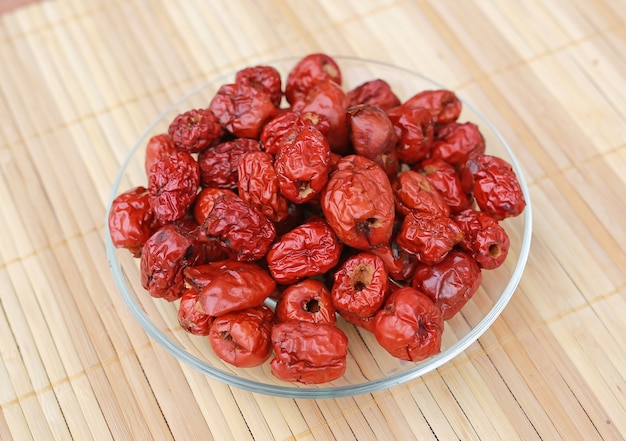 Foto jujube, chinees droog rood datumfruit op een plaat tegen houten achtergrond.