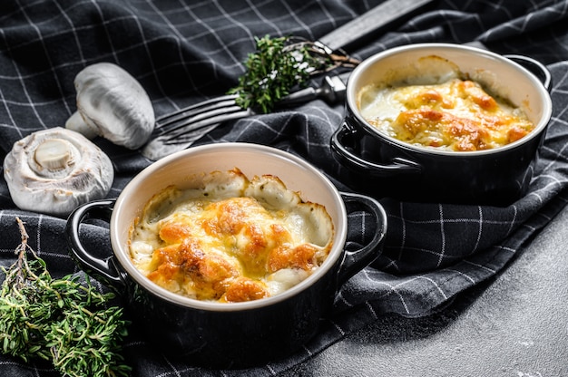 Julienne with chicken and mushroom in portion forms. Black background. Top view