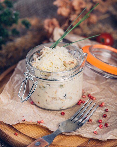 Julienne with chicken and mushrooms in a glass serving jar sprinkled with Parmesan cheese.