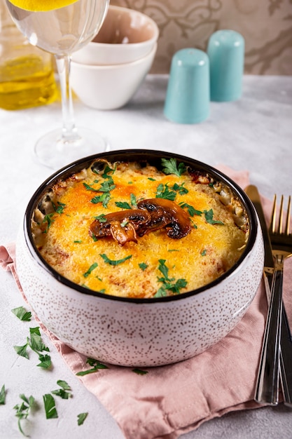 Julienne con patate e funghi in una teglia su un tavolo luminoso foto verticale tradizionale