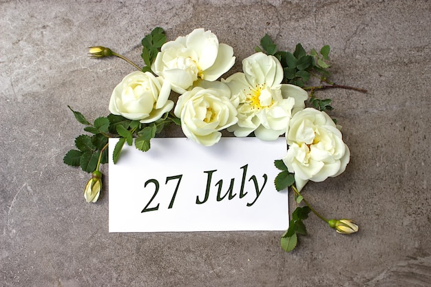 Photo july 27th. day 27 of month, calendar date. white roses border on pastel grey background with calendar date. summer month, day of the year concept.