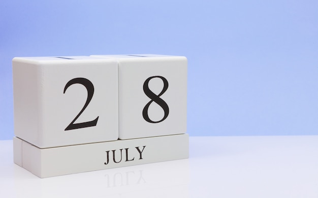 写真 7月28日月28日、反射、明るい青の背景を持つ白いテーブルに毎日のカレンダー。