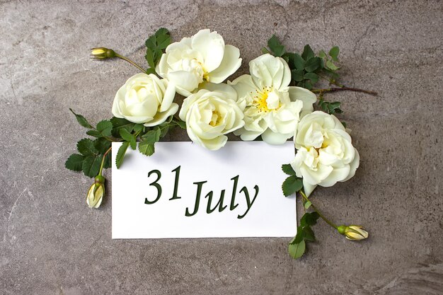 Foto 31 luglio. giorno 31 del mese, data di calendario. bordo di rose bianche su sfondo grigio pastello con data di calendario. mese estivo, concetto di giorno dell'anno.