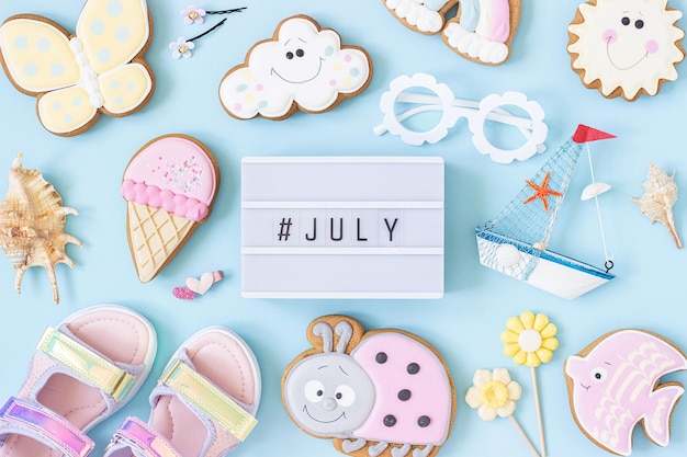 July text on lightbox and cute summer symbols on blue background Top view Flat lay Creative summer concept greeting card