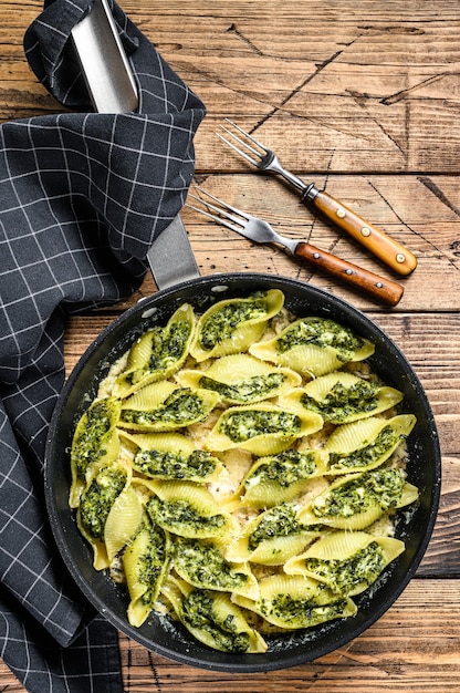 Jumbo schelpen pasta Conchiglioni gevuld met spinazie en kaas gebakken met saus in een pan