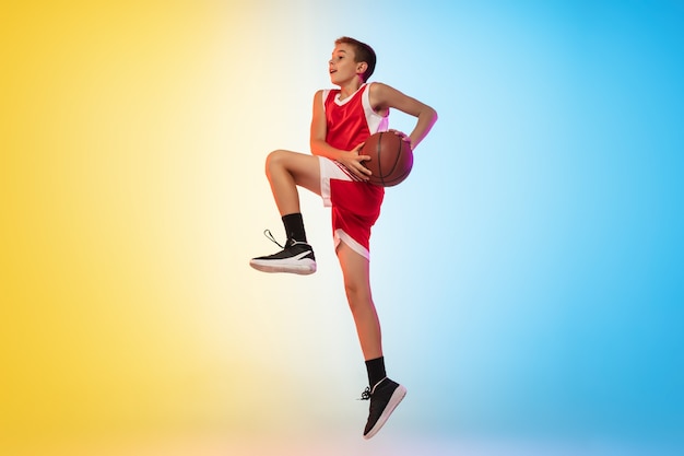 Jump high Full length portrait of young basketball player in uniform on gradient studio