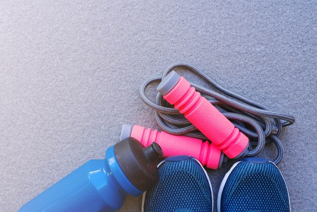 Photo jump rope, running shoes, and drink bottle on the ground