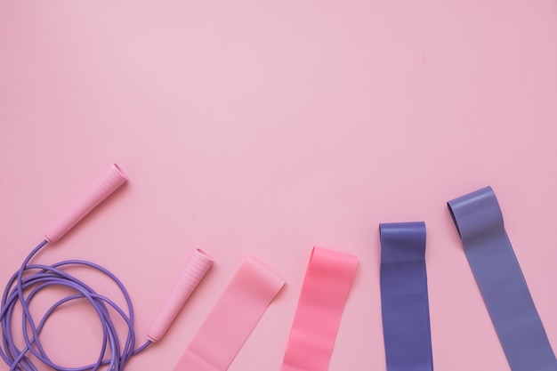 Jump or skipping rope  and fitness elastic band on pink background. Fitness trend.