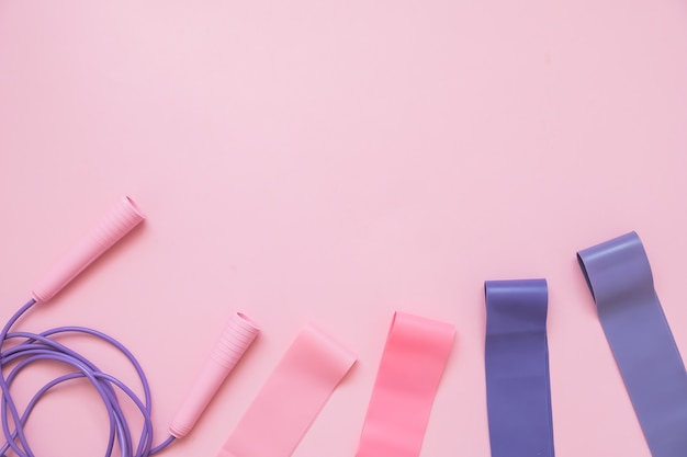 Photo jump or skipping rope  and fitness elastic band on pink background. fitness trend.