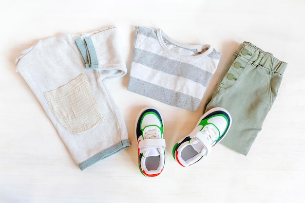 Maglia e pantaloni jeans con sneakers set di vestiti e accessori per bambini per la primavera, l'autunno o l'estate su sfondo bianco abito per bambini alla moda vista dall'alto piatta vista dall'alto