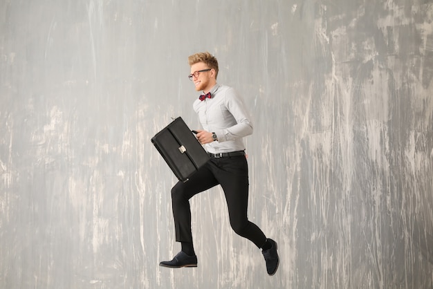 Jumping businessman with stylish briefcase on grey