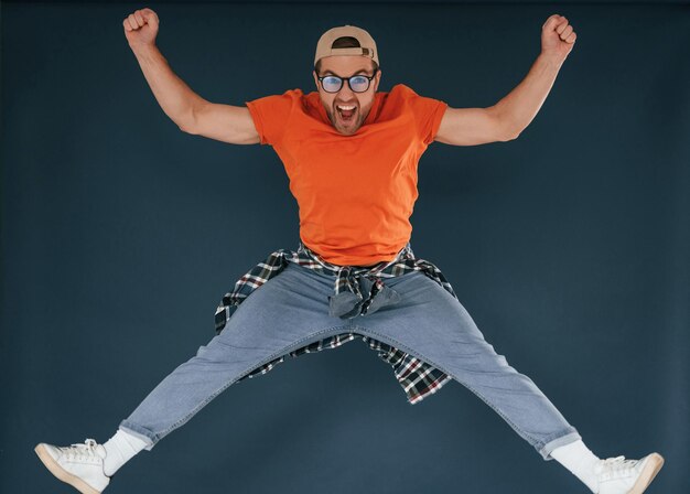 Photo jumping feeling good excited handsome man is in the studio against blue background