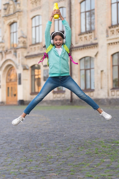 Jumping happy kid feel freedom and joy with water bottle outdoor, active and energetic childhood.