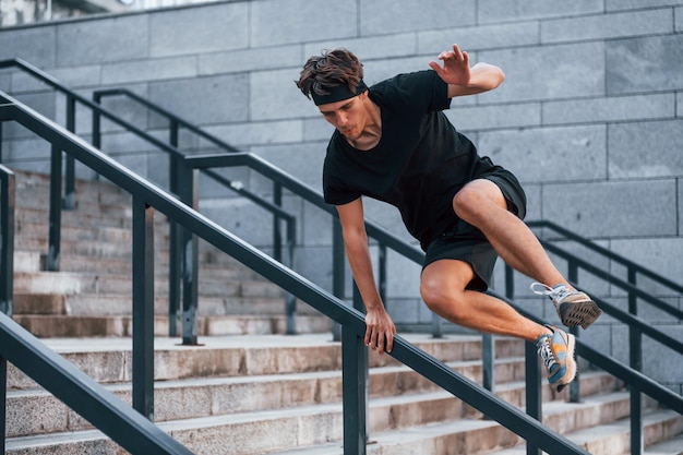 Прыжки через препятствия Молодой человек в спортивной одежде тренируется на открытом воздухе в дневное время