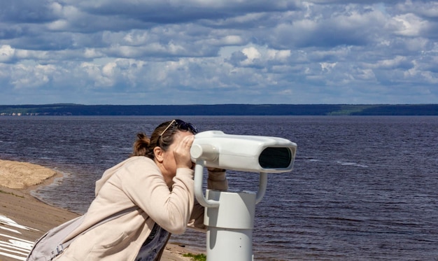 On June 19 2022 in Cheboksary a woman looks through a binocular telescope at tourists on the embankment