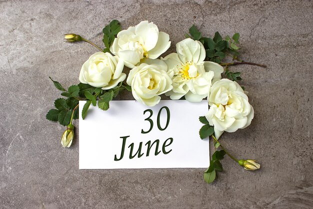 June 30th. Day 30 of month, Calendar date. White roses border on pastel grey background with calendar date. Summer month, day of the year concept.