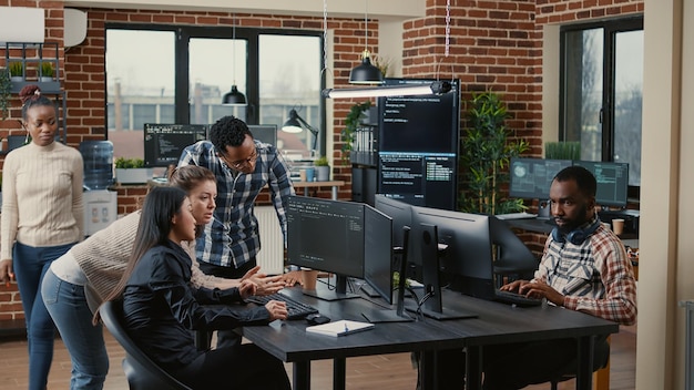 Junior dev programmers collaborating on group project compiling algorithm asking senior developer for help while intern joins the discussion. Software engineers brainstorming ideas looking at screens.