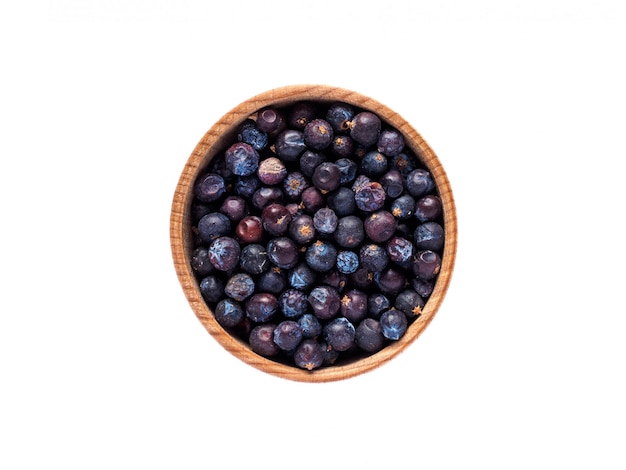 Juniperus fruit in wooden cup on white table