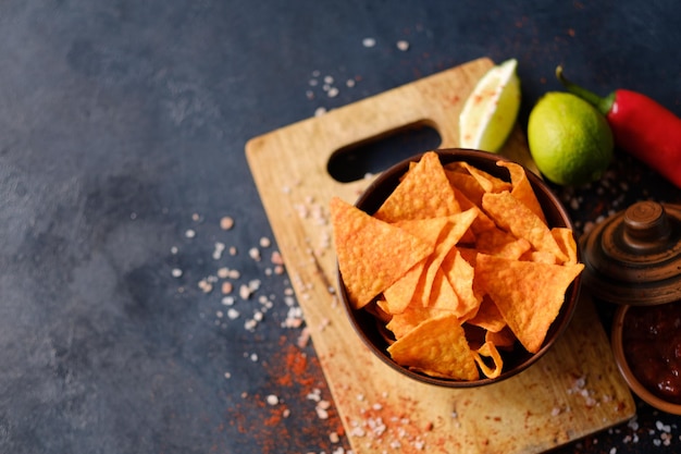 Junk fast food en ongezond eten nacho tortillachips in een kom knapperige driehoekige chips op donkere achtergrond