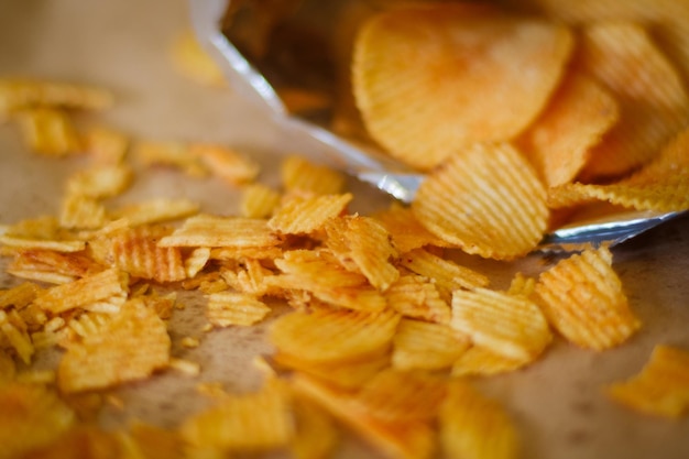 Junk fast food and unhealthy eating crispy chips scattered on the surface crunchy potato crisps pouring from a bag