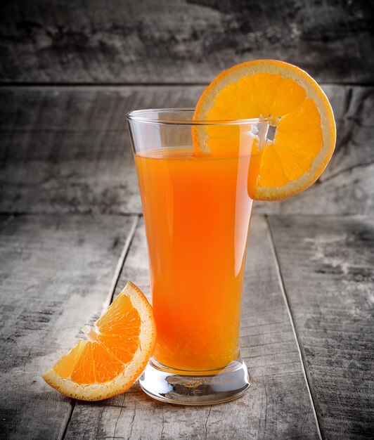 Jus d'orange glas en verse sinaasappelen op hout