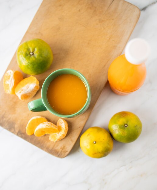 Foto jus d'orange in een beker en in een fles op marmer