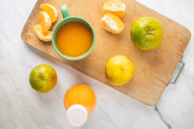 Foto jus d'orange in een beker en in een fles op marmer