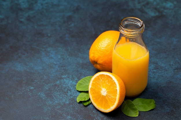 Jus d'orange in glazen fles en rauwe sinaasappel