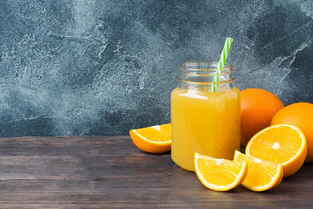 Jus d&#39;orange in glazen pot en vers fruit sinaasappelen op donkere achtergrond met kopie ruimte.