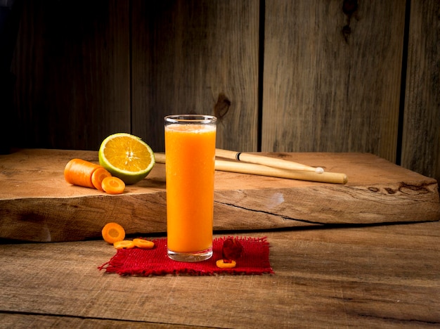 Jus d'orange met wortel met, plakjes sinaasappel en wortel op houten achtergrond.