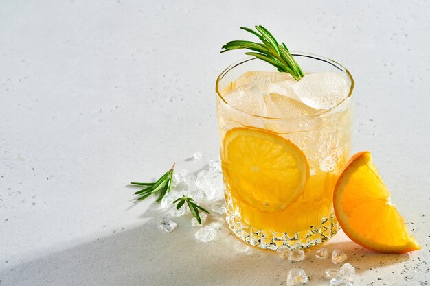 Jus d'orange of cocktail met rozemarijn en sinaasappel met ijs in glas, koude zomerlimonade