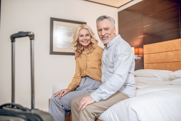 Just arrived. Good-looking couple sitting on a bed in in a hotel room