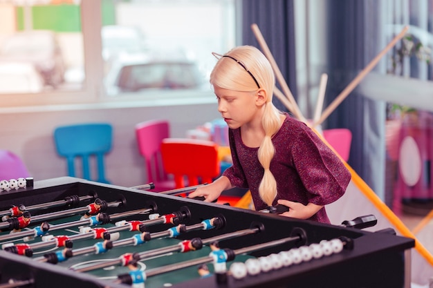 Just attention. Beautiful longhaired kid bowing head and playing artificial football