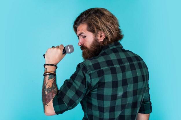 Just fabulous hair brutal and rock bearded man wear checkered\
shirt singing song male singer with mic concept of karaoke man\
singer love music brutal man sing with microphone vocal school