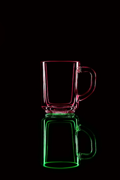 Solo un bicchiere su uno sfondo nero con un riflesso. rosso e verde. isolato.