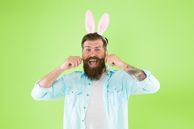 Foto basta far crescere i capelli uomo barbuto indossare orecchie da coniglio sfondo verde hipster con peli sul viso in stile pasquale baffi a manubrio parrucchiere barbiere tenere i capelli fuori dalla bocca