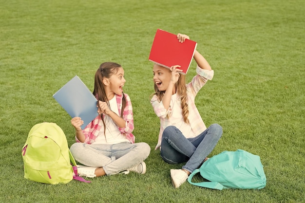 Just have fun small kid friends relax on grass back to school literature for girls do homework together find something interesting in book making notes spend free time after school