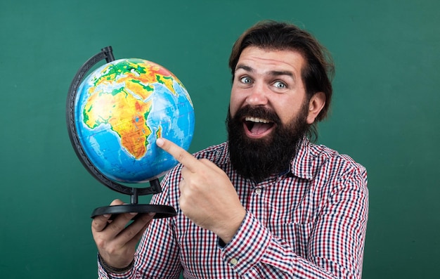 Just look here nonformal education male student in school classroom while geography lesson pass the exam learning the subject happy geographer man with beard look at globe ready for studying